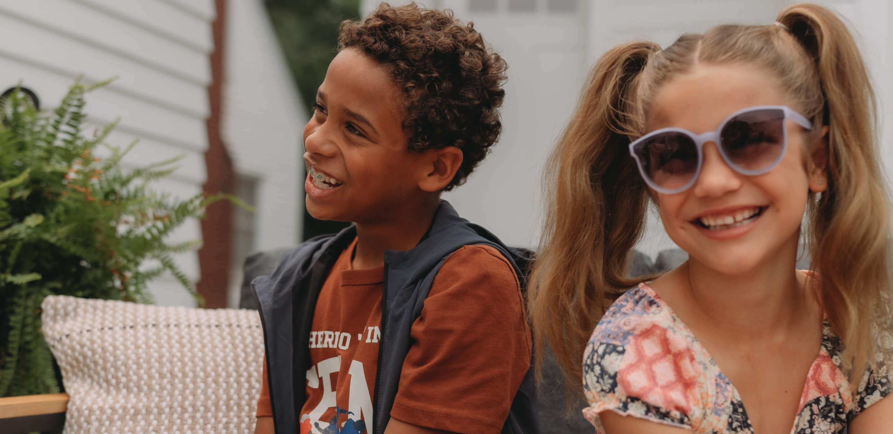 Two happy children, girl wearing sunglasses and smiling, enjoying together